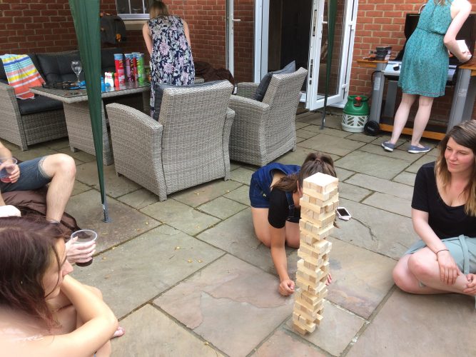 Group of people playing garden tumble tower on the patio