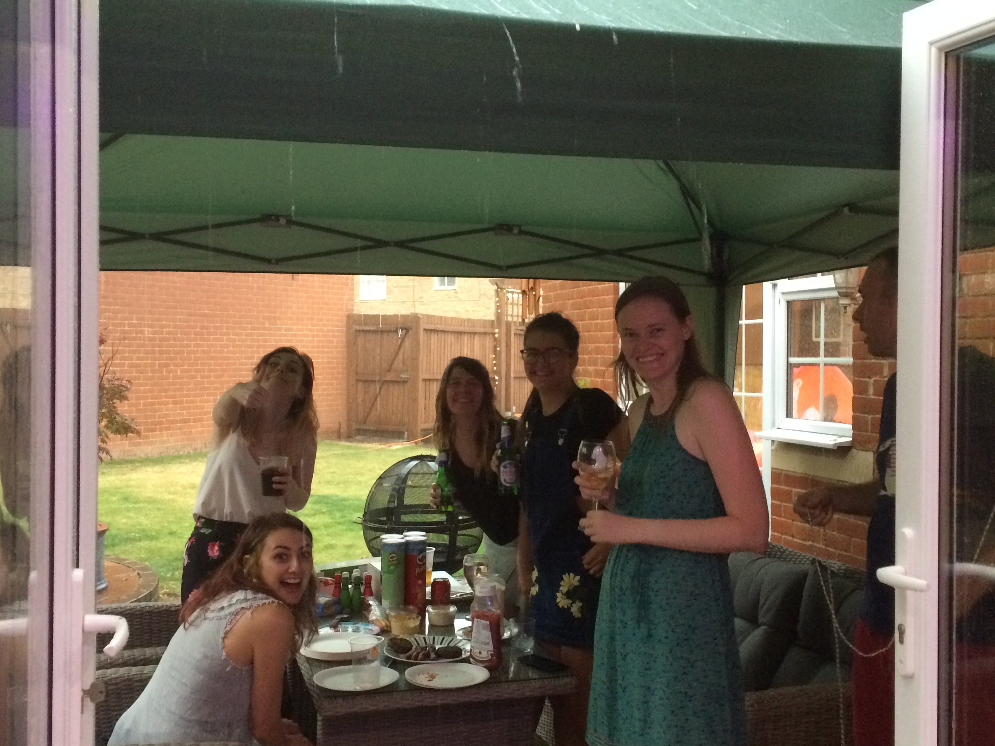 Group of us happily gathered under the gazebo as rain pours outside