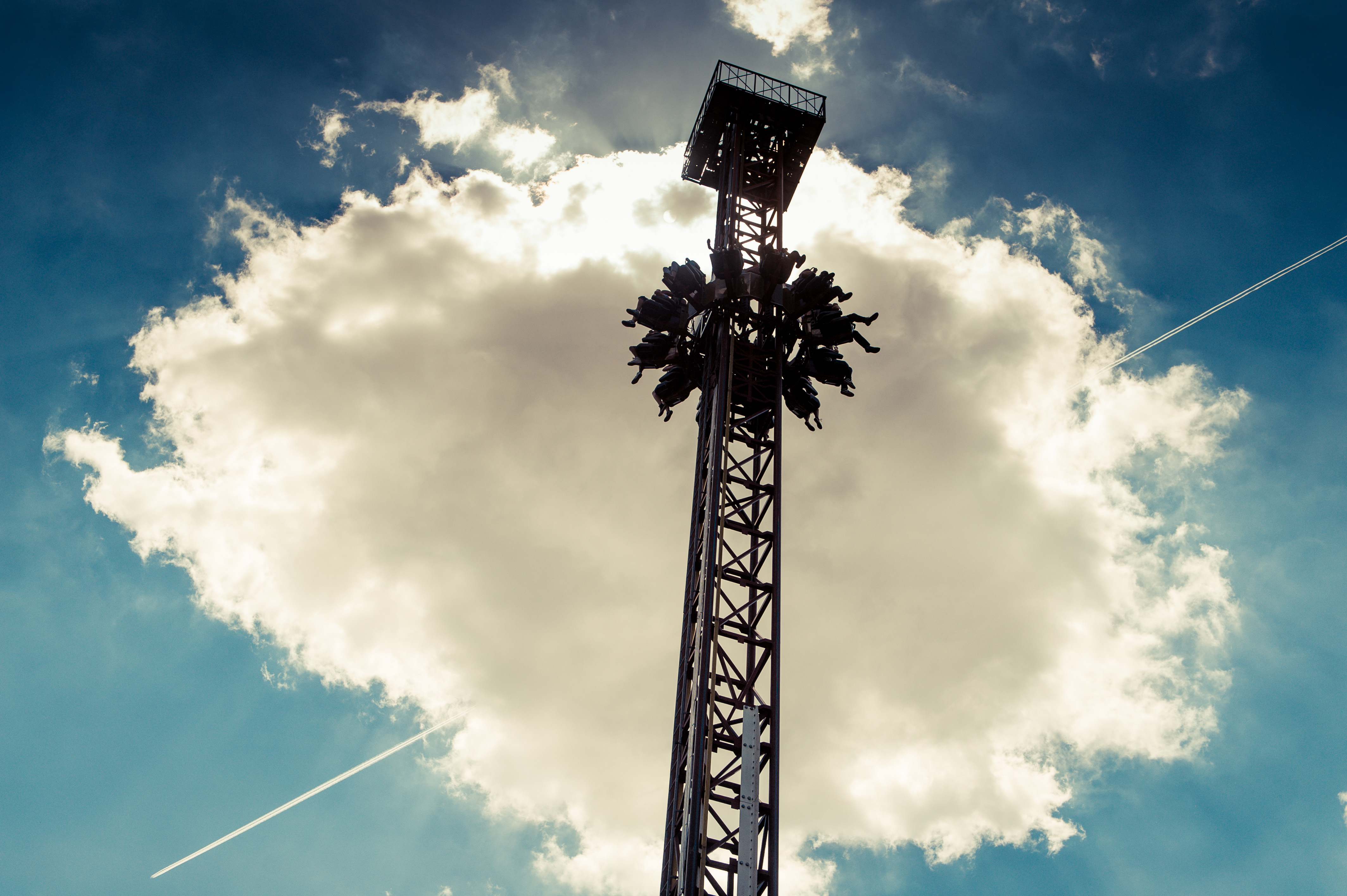 A tall metal structure with people in seats being lifted up to the top.