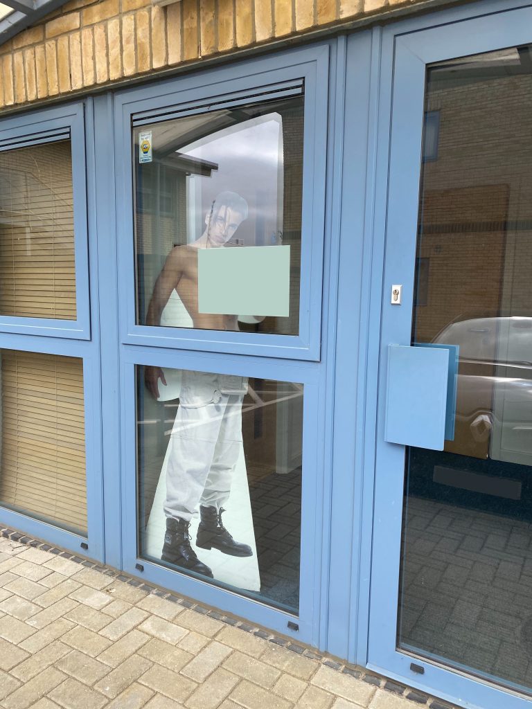 A glass office door with a Peter Andre cardboard cutout inside.