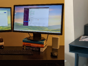 Two pictures of computer desks. One has two monitors balanced on stacks of books, plus a laptop. The other is a multi level deep navy desk with gold fittings and two monitors.